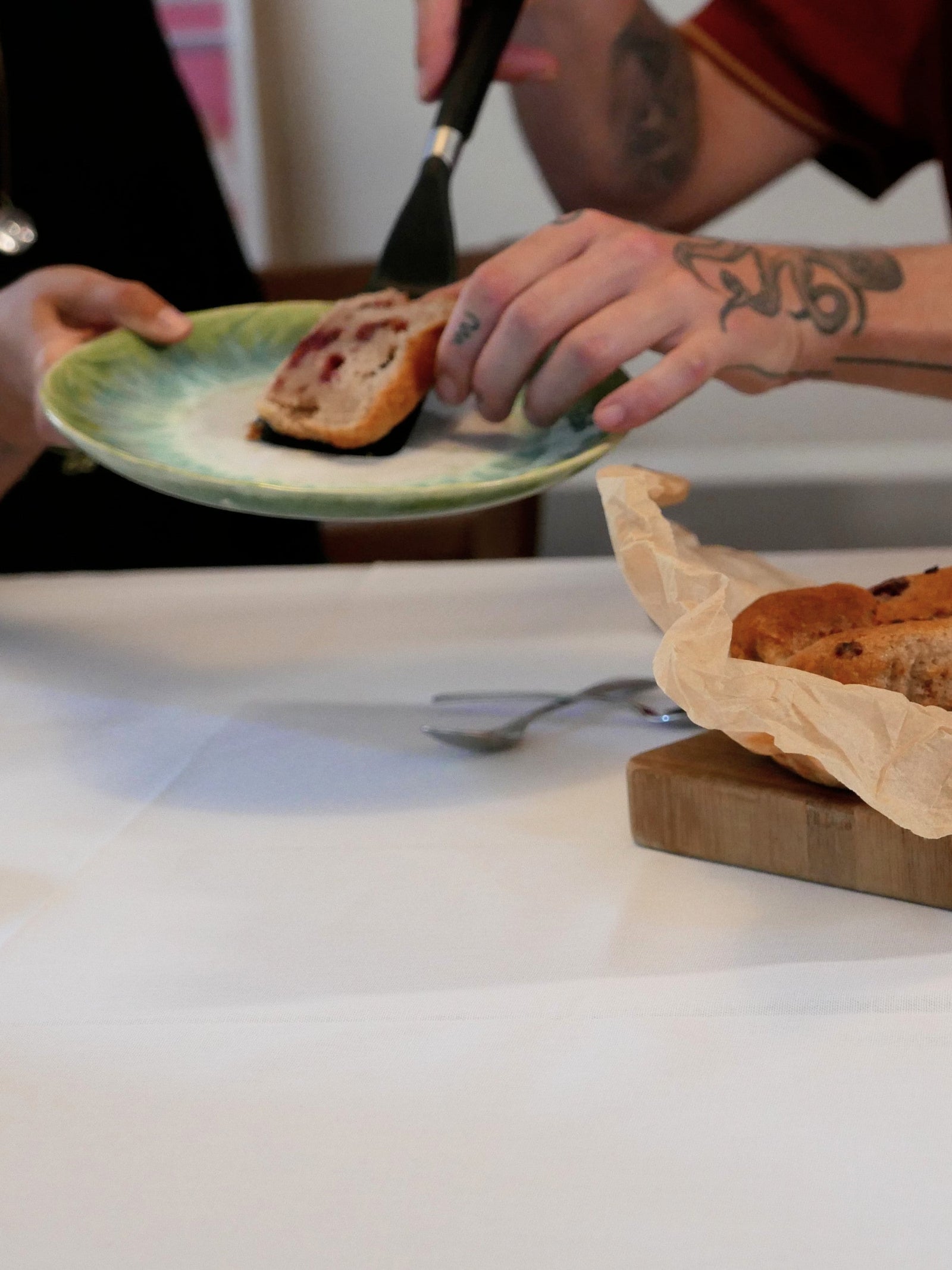 Person cutting a piece of raspberry lemon loaf on a plate with a knife