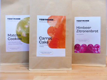 Three Tortmann baking mix packages on a wooden surface with visible labels.